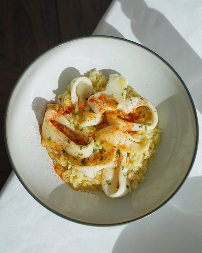 Top view of a savory squid ink risotto served in a bowl, illuminated by natural light.